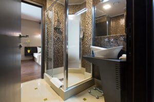 Elegant bathroom featuring a glass shower screen with mosaic tile walls, modern sink, and large mirror. This well-designed space highlights potential areas to check for a shower screen leak.