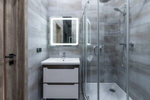 Contemporary bathroom featuring a glass shower screen with double doors, a corner shower unit, LED mirror, and sleek vanity unit. This modern setup is ideal for identifying a potential shower screen leak.