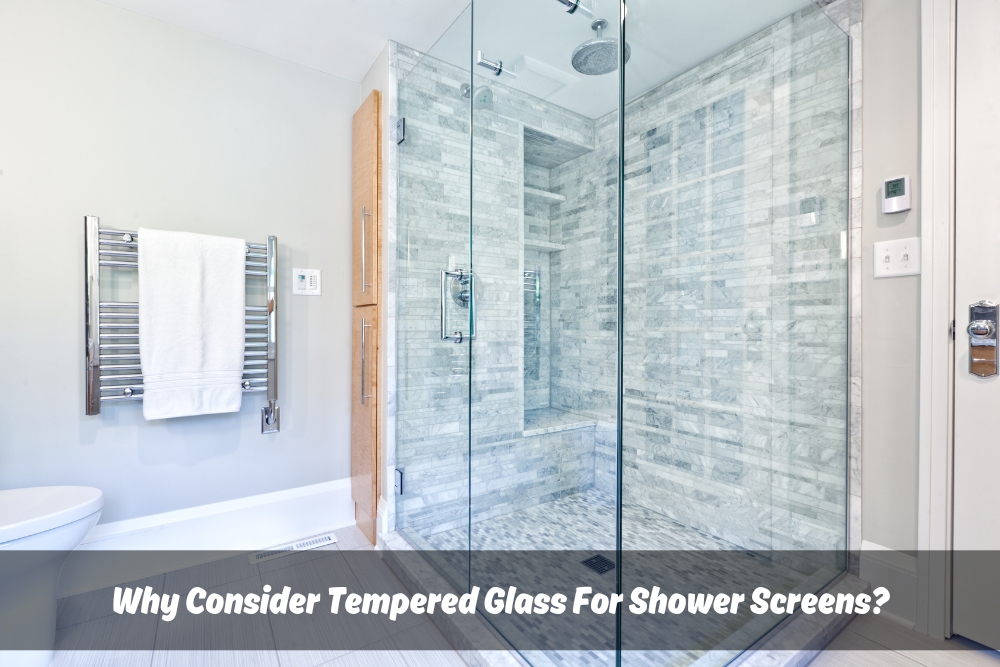 Clear tempered glass for shower screens in a modern bathroom featuring a chrome towel rack, brown cabinets, and a toilet. Inside the tempered glass shower screen are grey tiles and a sleek shower.