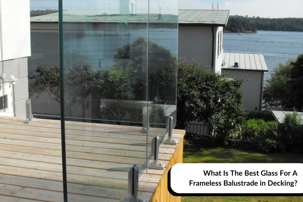 A clear frameless glass balustrade installed on a wooden deck overlooking a scenic waterfront view. The modern glass panels are securely mounted with stainless steel clamps, providing an unobstructed view of the surrounding landscape. The setting highlights the elegance and safety features of using a frameless glass balustrade for decking.